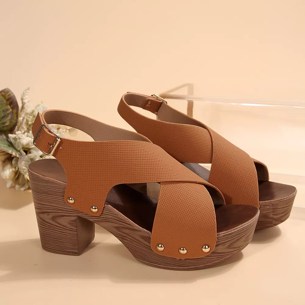 Brown crisscross high heel sandals with adjustable strap and stud details on a wooden block heel.