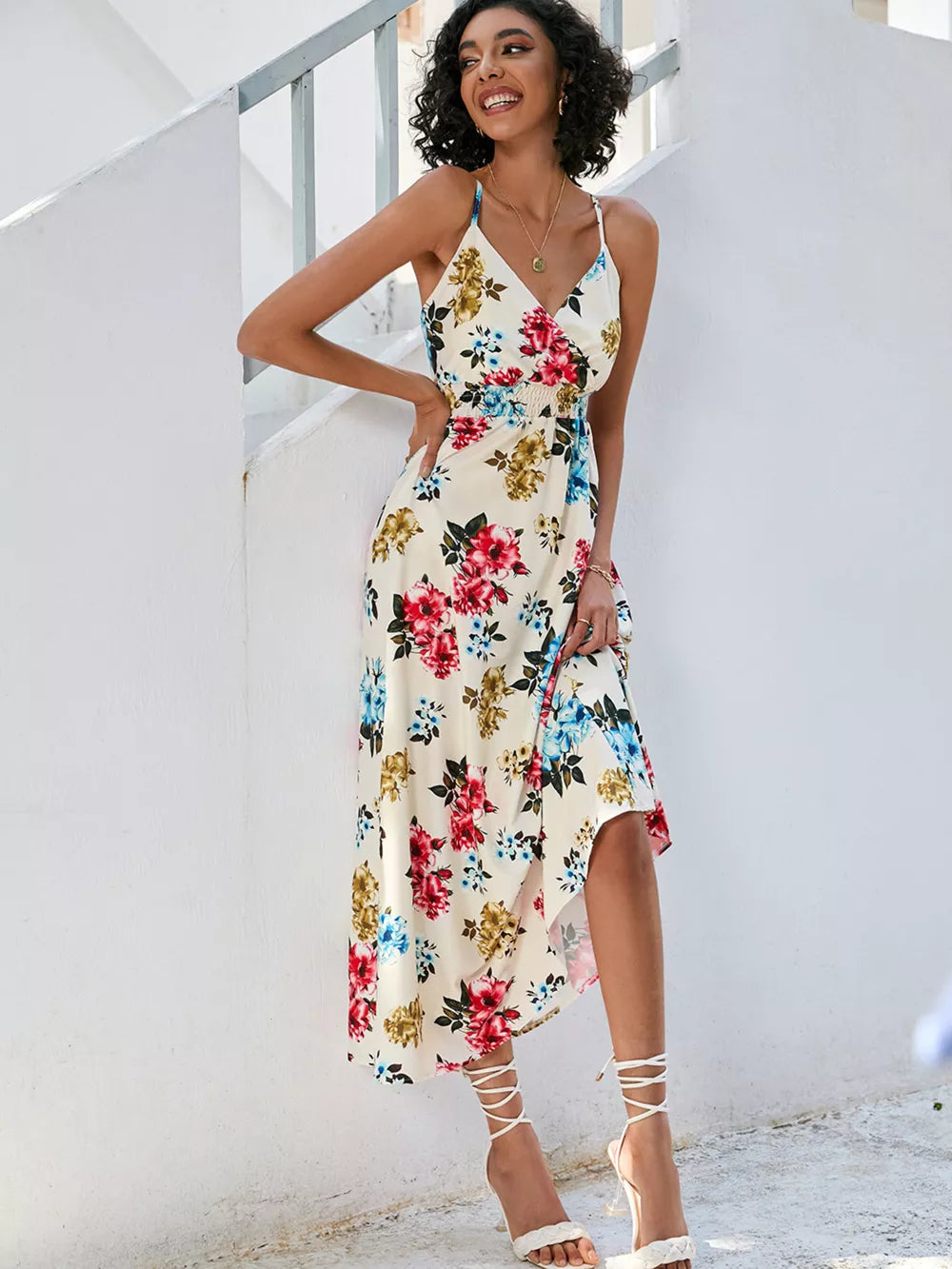 Chic floral midi dress with spaghetti straps, V-neck, and a wrap-style skirt in cream with red, blue, and yellow flowers.