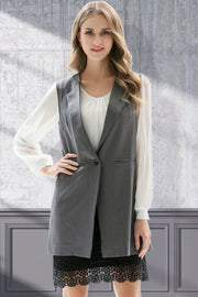 Mid gray tailored sleeveless vest with single button closure and notched lapels, worn over a white blouse.
