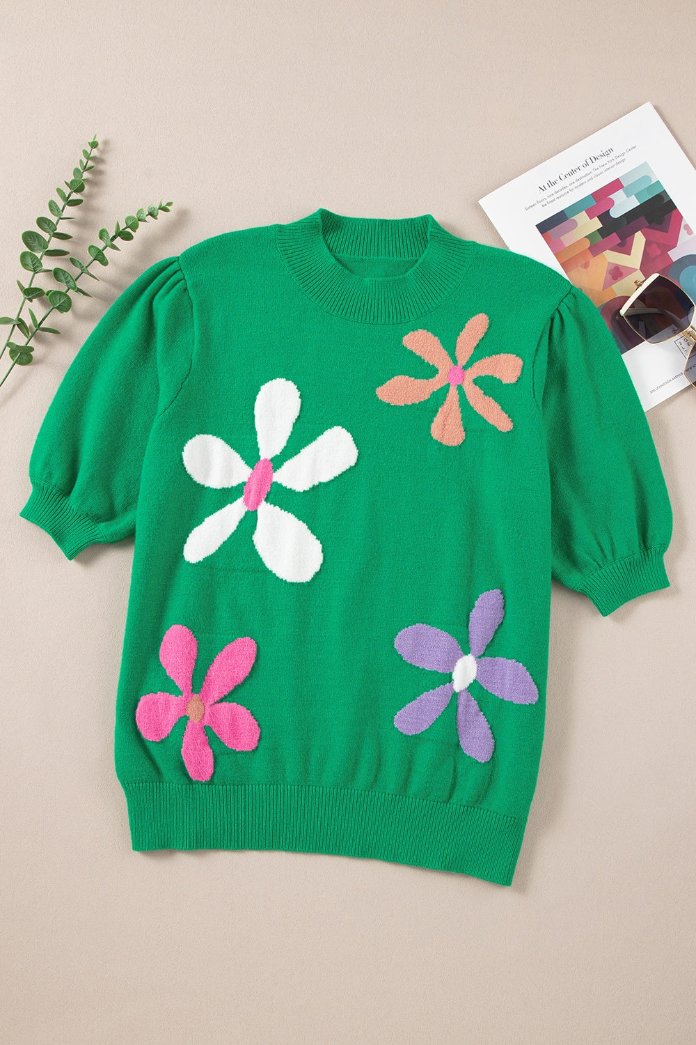 Green knit top with puff sleeves and colorful floral appliques.