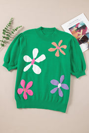 Green knit top with puff sleeves and colorful floral appliques.