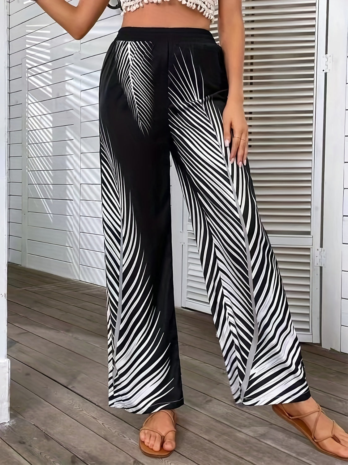 Black and white palm print palazzo trousers with a wide leg cut.