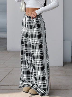 Black plaid wide-leg track pants with white drawstring and gray side stripe.