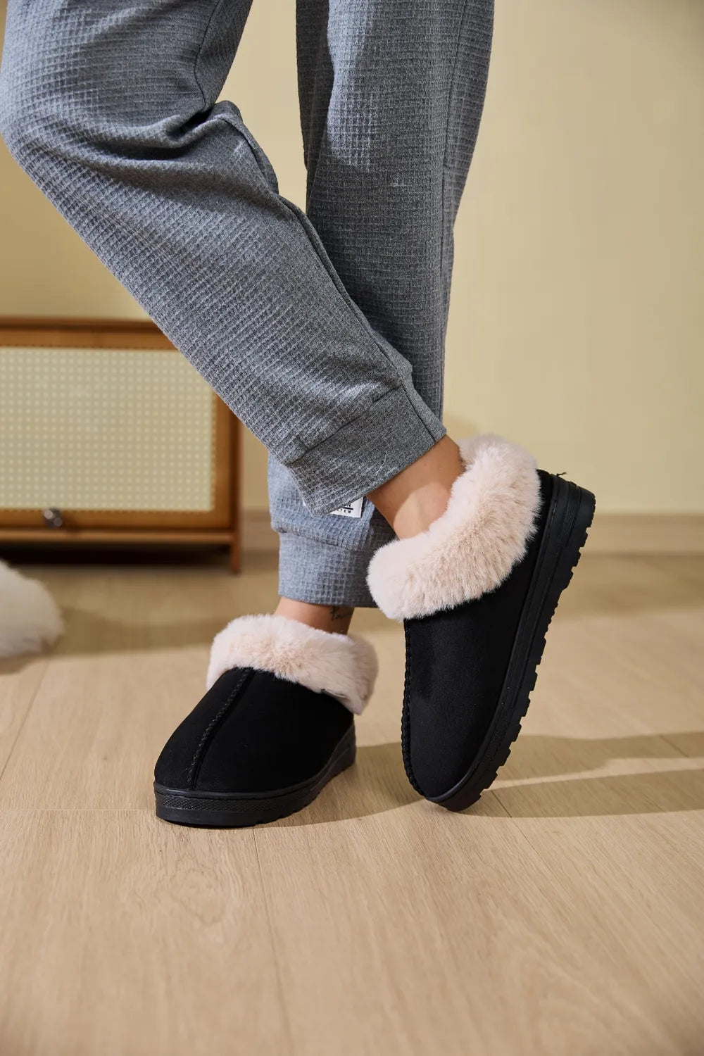 Black suede shearling-trimmed house slippers with plush lining.
