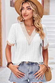 White eyelet blouse with lace trim V-neck and short sleeves, styled with denim shorts.