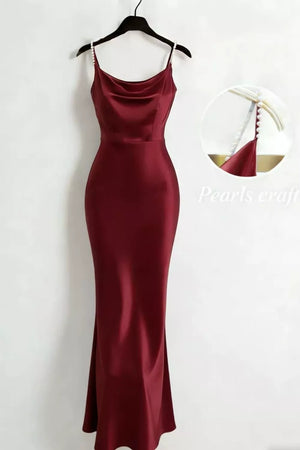 Burgundy satin cowl neck maxi dress with pearl-embellished spaghetti straps.