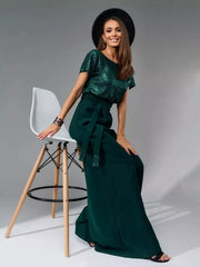 Dark green sequin wide-leg jumpsuit with tie waist and flowing pants.