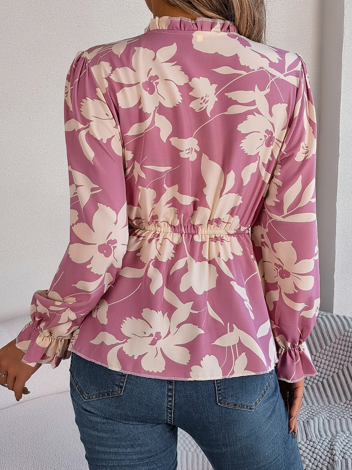 Floral peplum blouse with ruffled neck in pink purple, cinched waist, and ruffled cuffs.