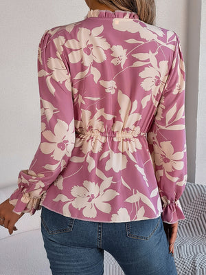 Floral peplum blouse with ruffled neck in pink purple, cinched waist, and ruffled cuffs.