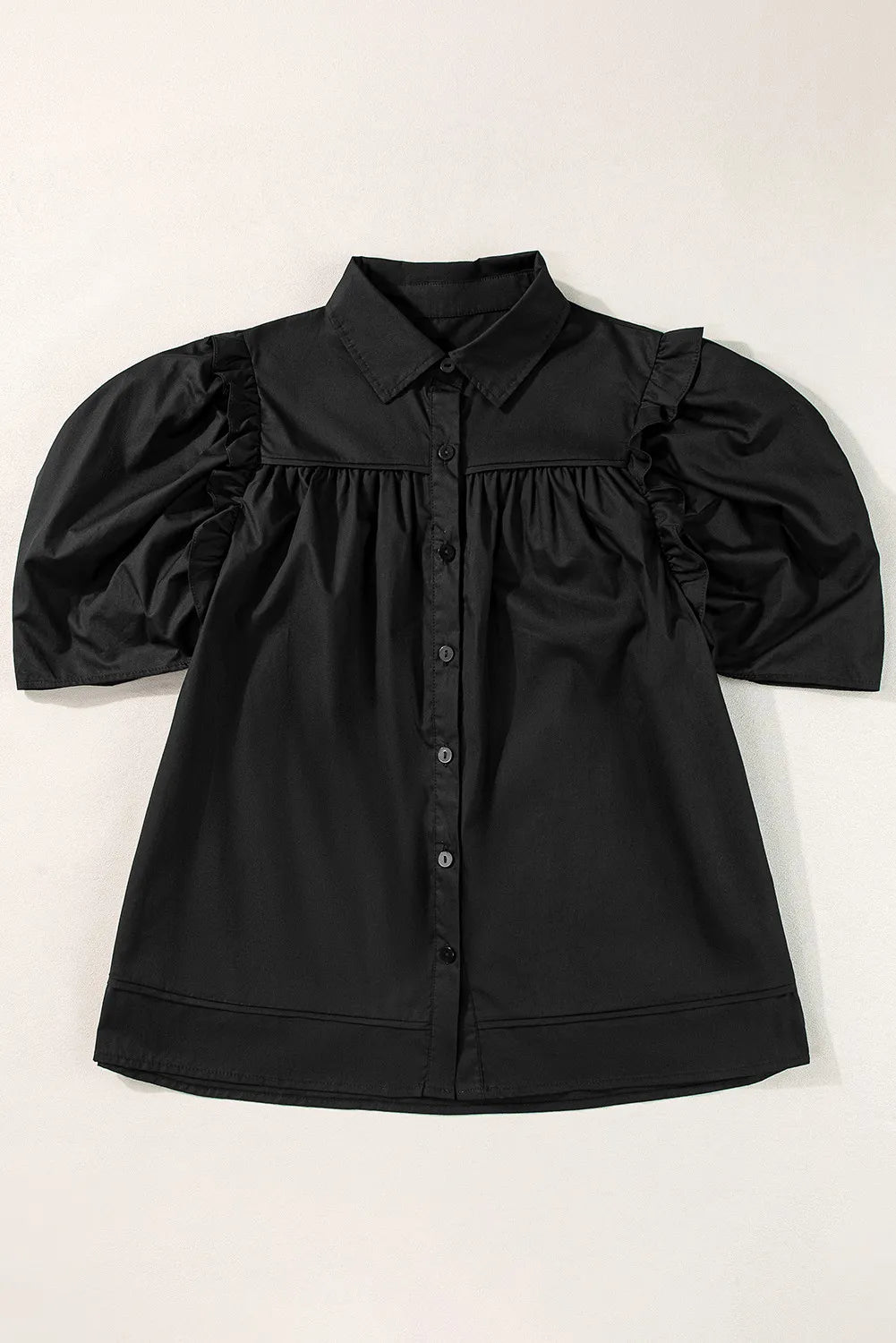 Black poplin blouse with gathered puff sleeves, button front, and ruffled shoulder detail.