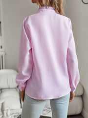 Blush pink textured blouse with ruffle collar and long sleeves.