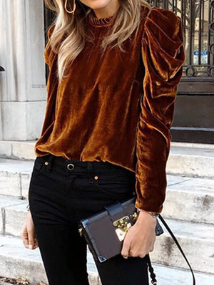 Brown velvet mock neck blouse with ruffled shoulders and long sleeves.