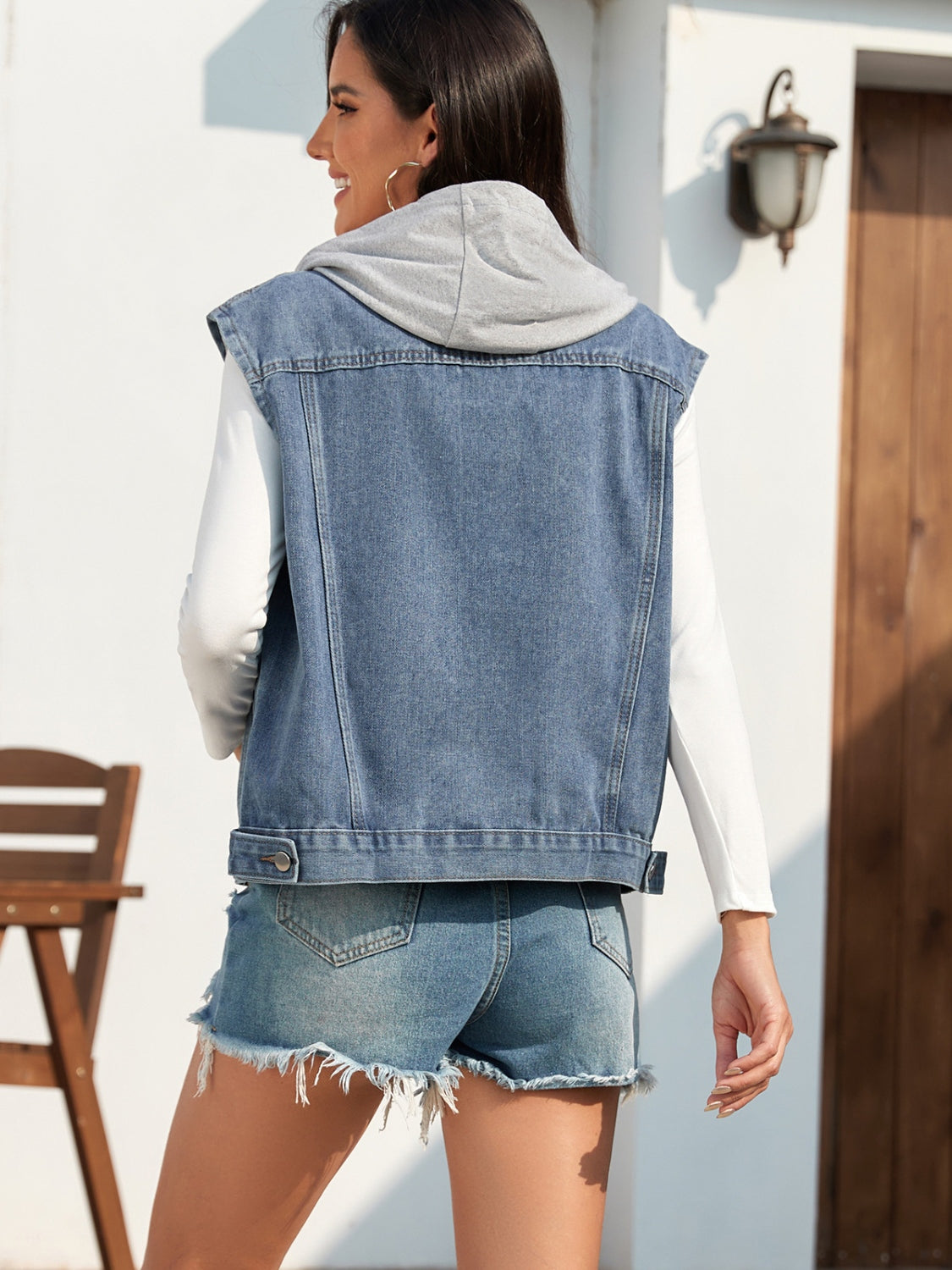 Sleeveless denim vest in medium blue with a grey hood detail.