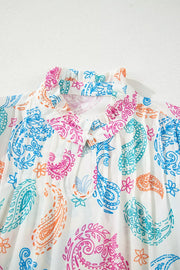 Maternity blouse with vibrant paisley print, ruffled neckline, and tie cutout.