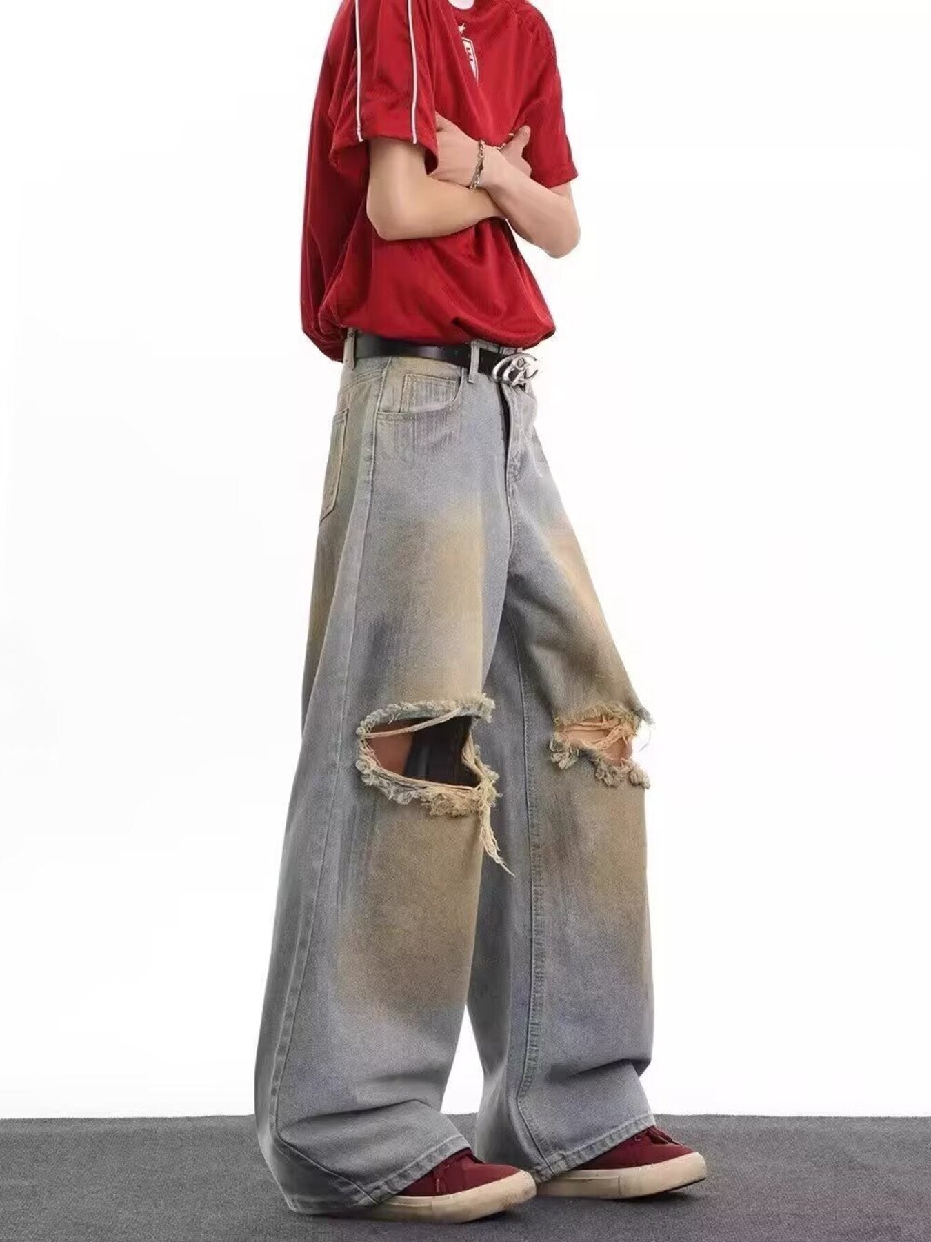 Men's distressed wide leg jeans in blue denim with large ripped knees and faded details.