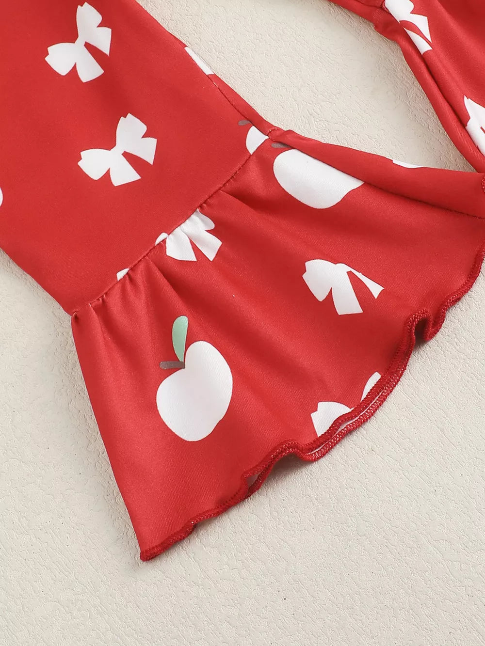 Red cotton bodysuit with white apple and bow print, ruffled bell sleeves.