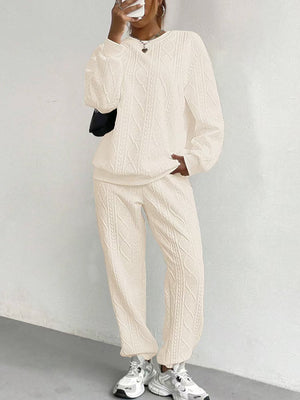 Beige cable knit loungewear set with crewneck sweatshirt and relaxed fit pants.