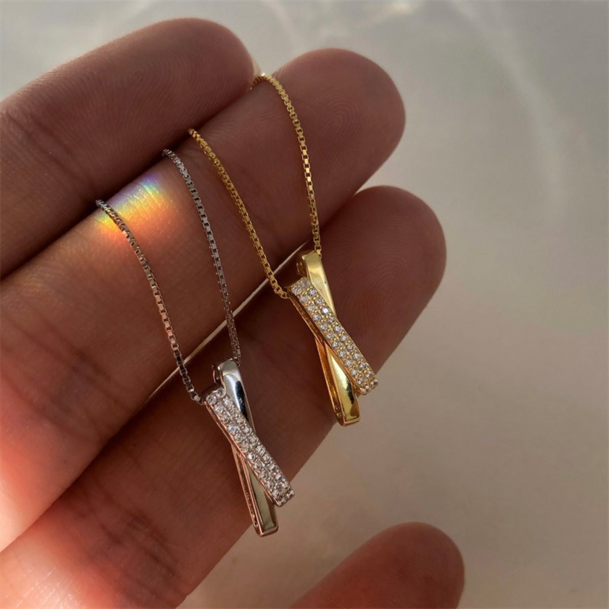 Sterling silver and gold crossover pendant necklaces with pave zircon details on box chains.