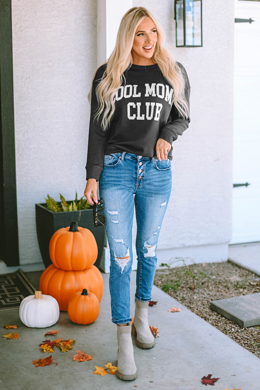 Charcoal crewneck sweatshirt with white "Cool Mom Club" graphic, styled with ripped jeans.