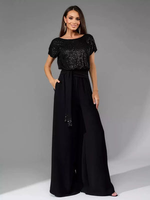 Black sequin wide-leg jumpsuit with tie waist and short sleeves.