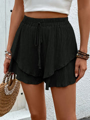 Black tiered gauze drawstring shorts with ruffled hem detail.