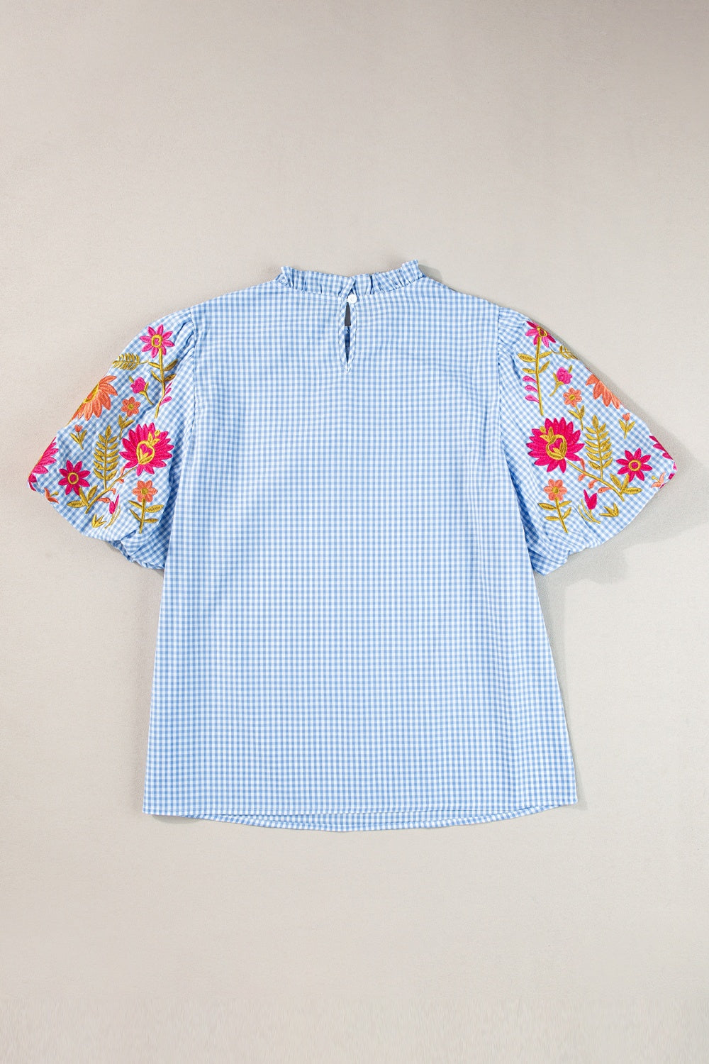 Light blue gingham blouse with embroidered floral puff sleeves and ruffled mock neck.
