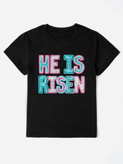 Black crewneck t-shirt with sequin "He Is Risen" graphic in pink and aqua.