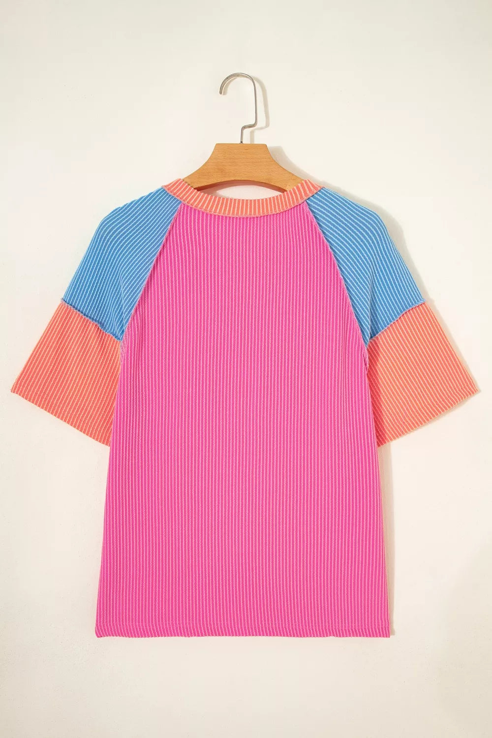Vibrant ribbed V-neck t-shirt with color block sleeves in pink, blue, and orange.