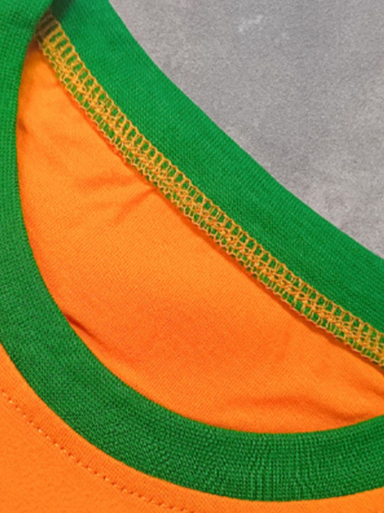 Orange cotton crew neck t-shirt with green trim and yellow stitching detail.