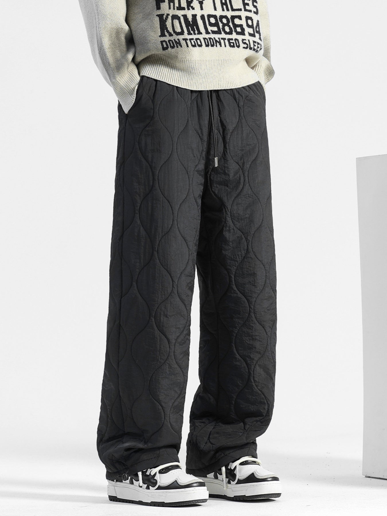 Men's black quilted sweatpants with relaxed fit and drawstring waist.
