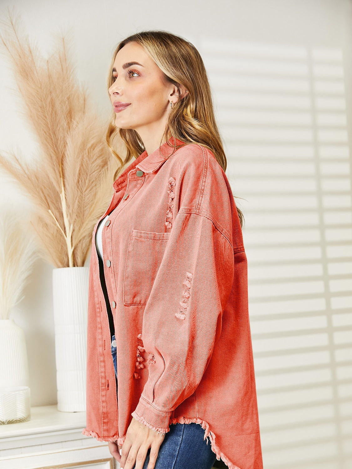 Distressed denim overshirt in orange-red with raw hem and buttoned front.