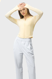 Light yellow zip-up active hoodie with thumbholes and pockets, cropped length.