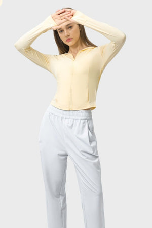 Light yellow zip-up active hoodie with thumbholes and pockets, cropped length.