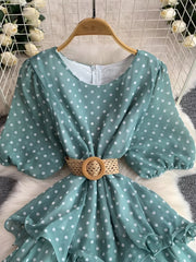 Green polka dot tiered dress with puff sleeves and a woven belt.