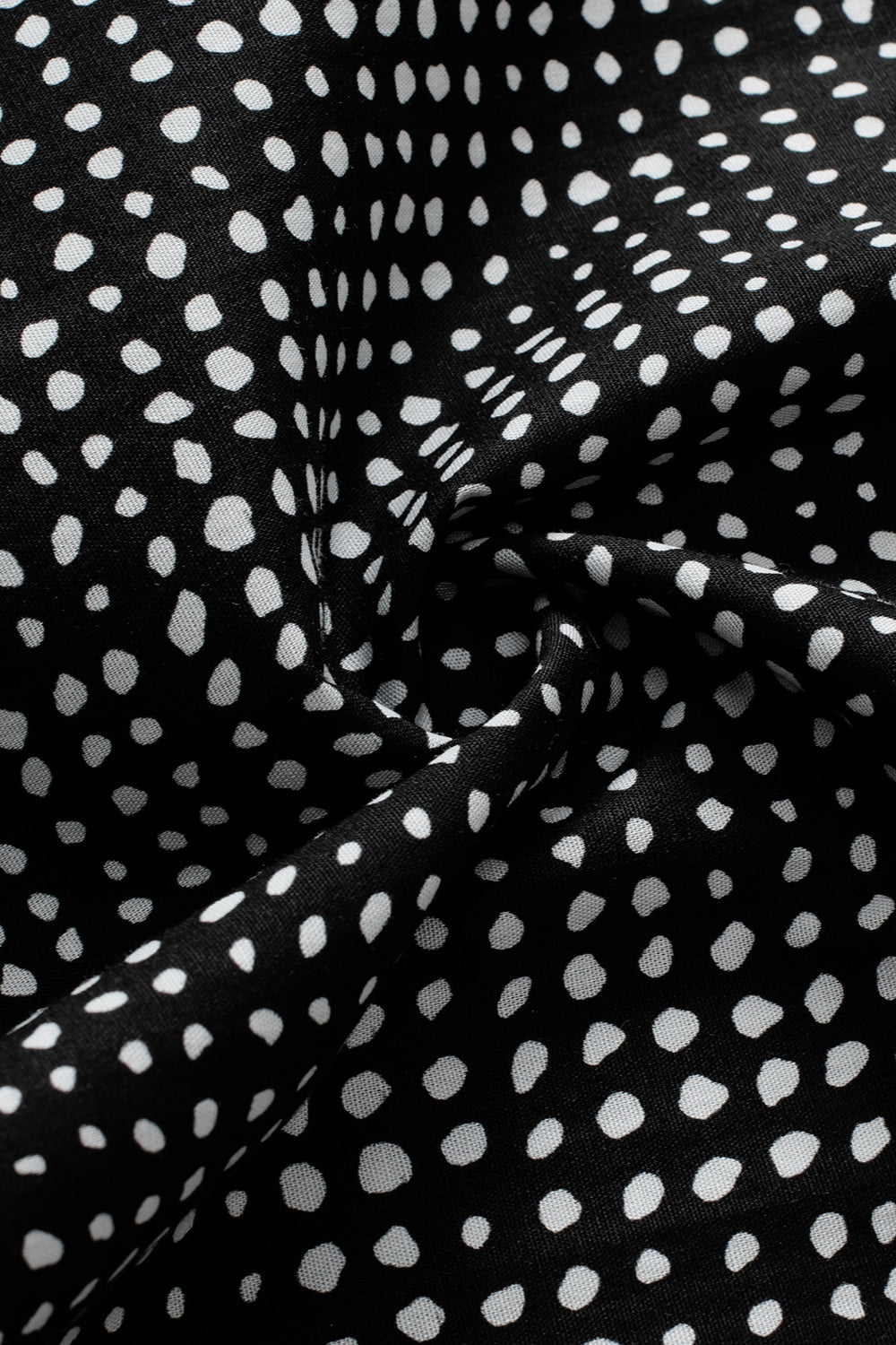 Black micro-dot blouse with puff sleeves and a swirling fabric detail.