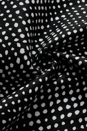 Black micro-dot blouse with puff sleeves and a swirling fabric detail.
