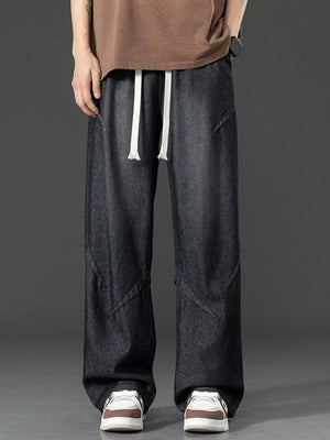 Men's dark wash oversized jeans with drawstring and unique paneling.