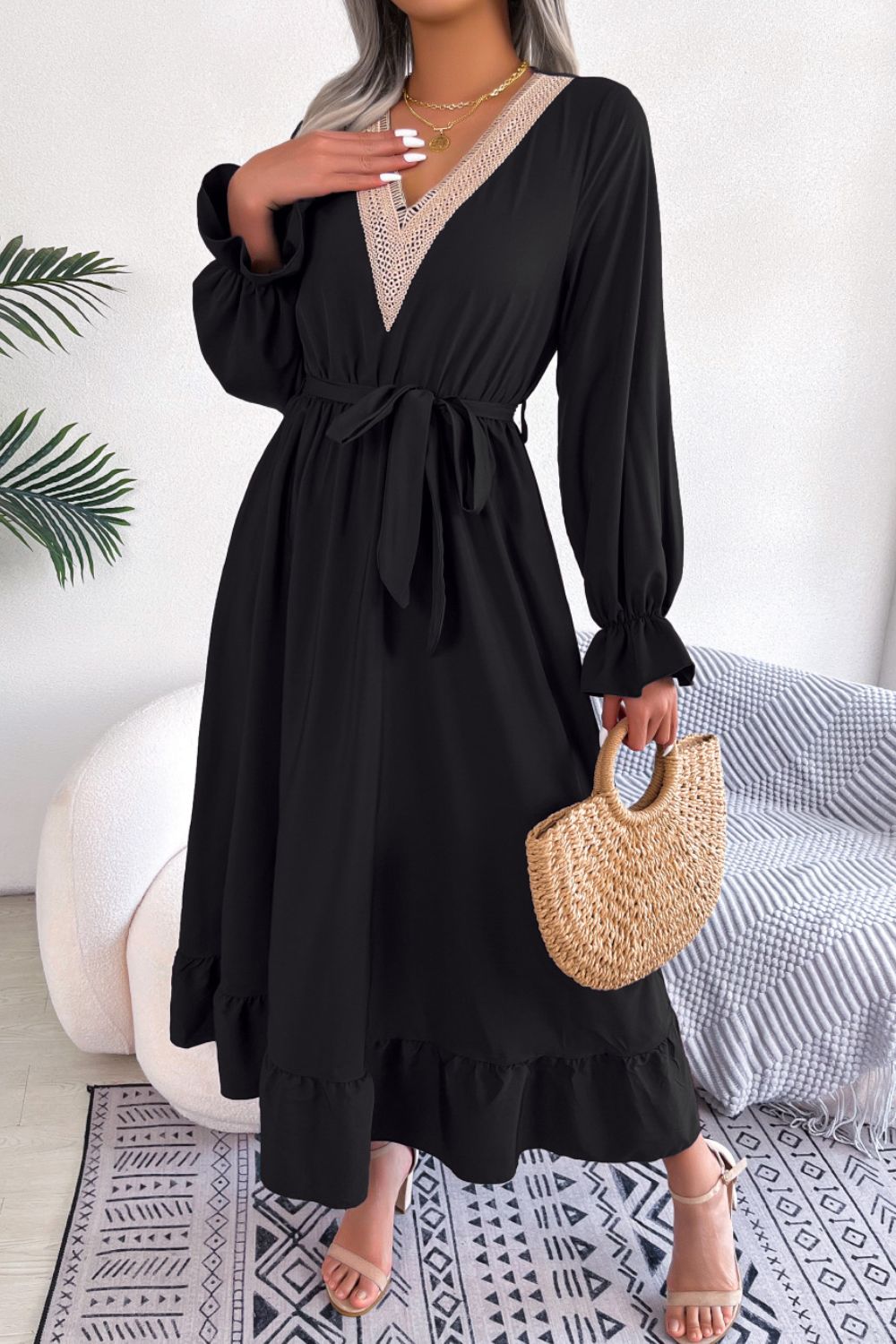 Black midi dress with lace trim V-neck, tie waist, long sleeves, and ruffled hem.
