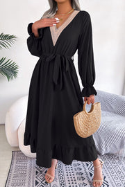 Black midi dress with lace trim V-neck, tie waist, long sleeves, and ruffled hem.