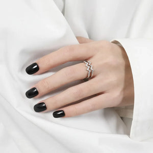 Silver zigzag split band ring with small stones on a hand with black nails.