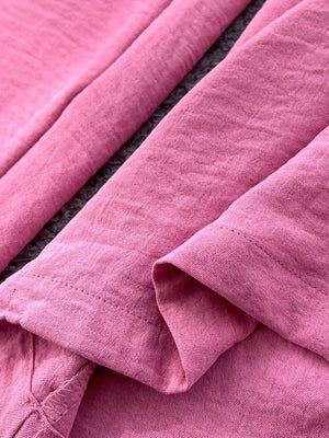 Pink cotton maternity jumpsuit with wide legs and belt detail.