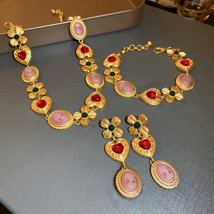 Gold bracelet with heart, cameo and floral charms, red and green stones