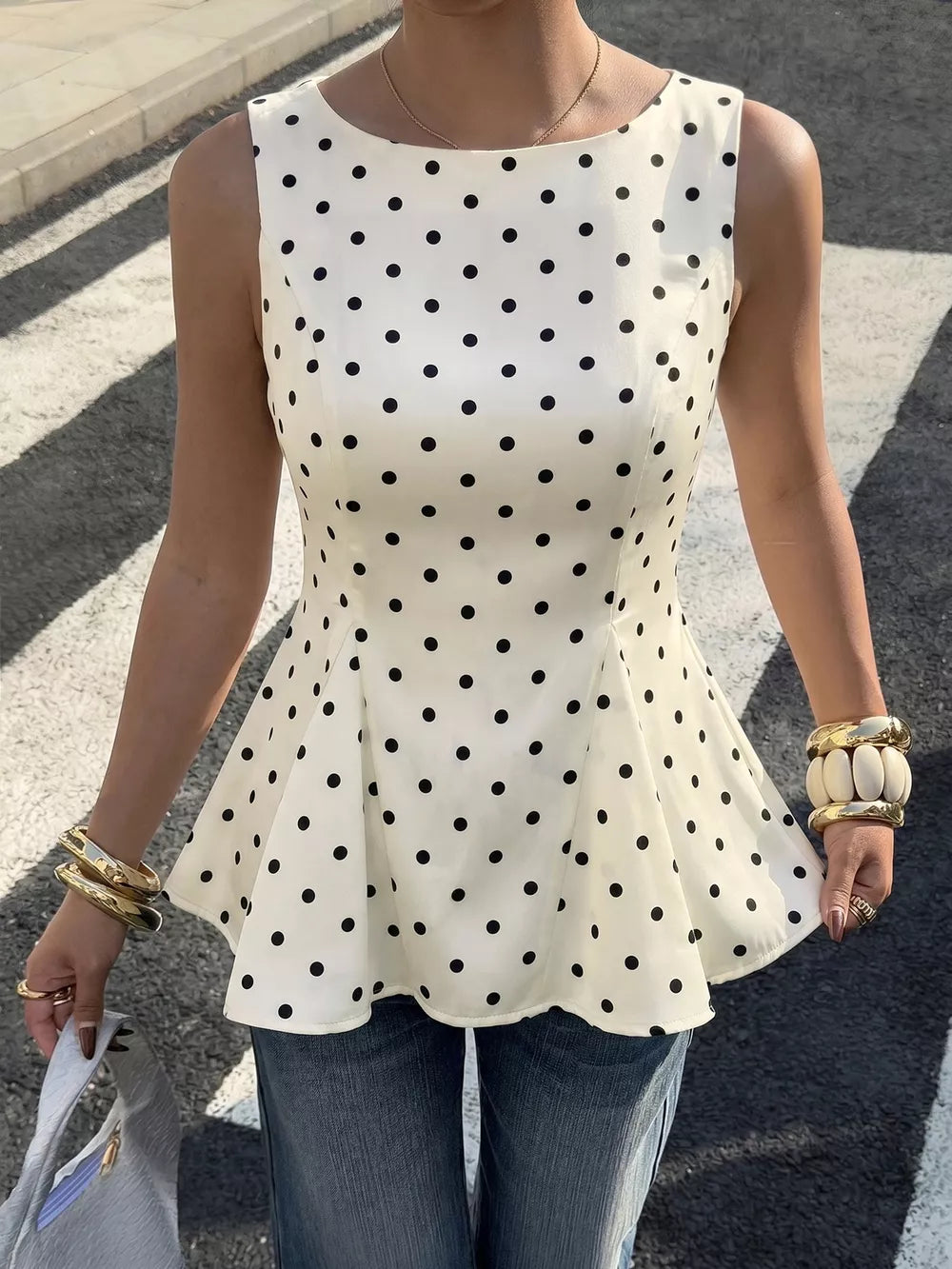 Chic white sleeveless peplum blouse with black polka dots and a boat neckline.