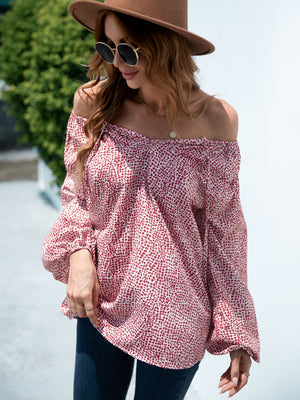 Off-the-shoulder blouson top in deep red with a spotted print and balloon sleeves.