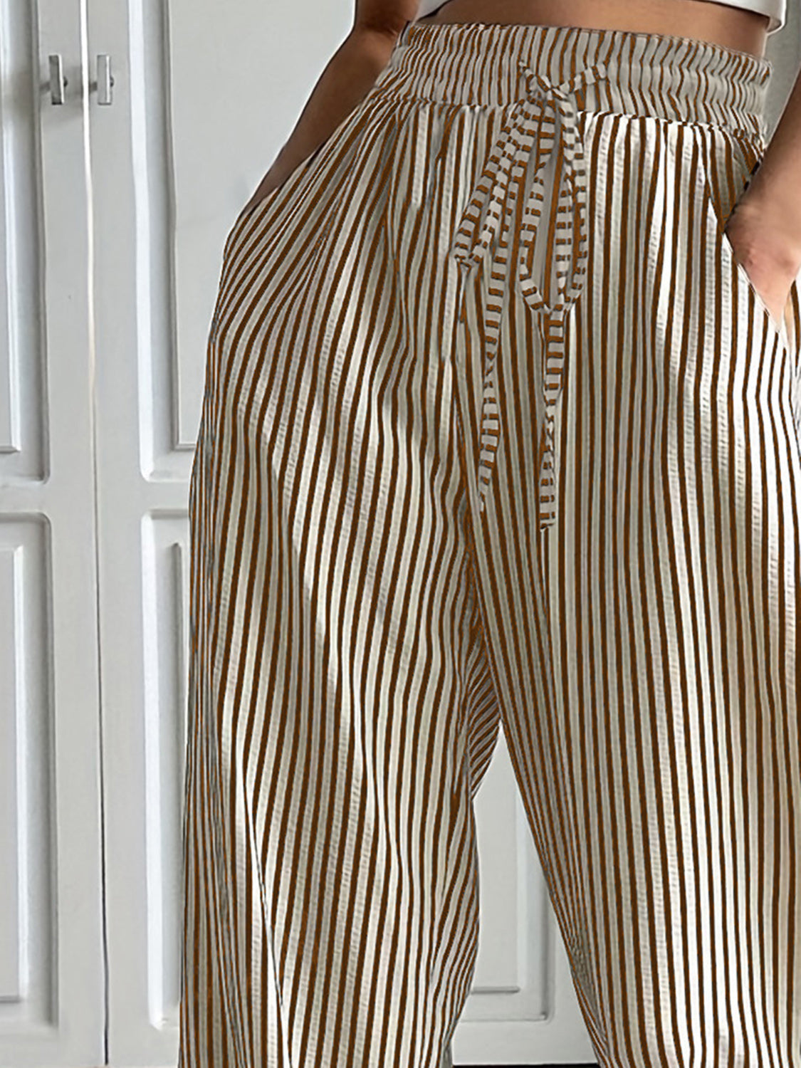 Wide-leg trousers in tan with vertical stripes and a drawstring waist.