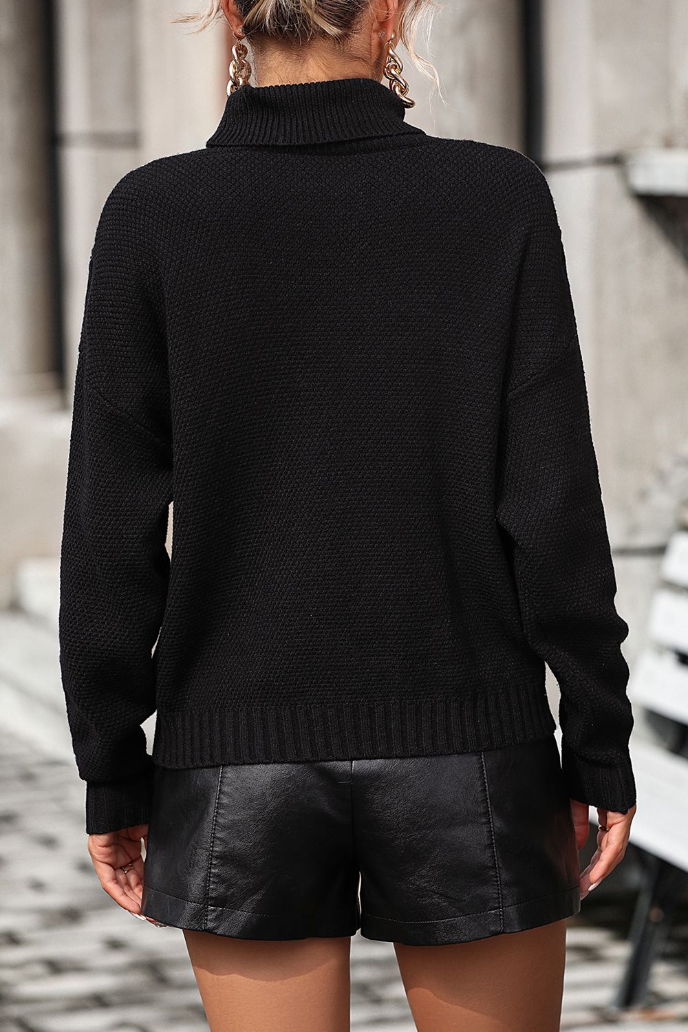 Black knit turtleneck sweater with textured pattern and ribbed cuffs and hem.