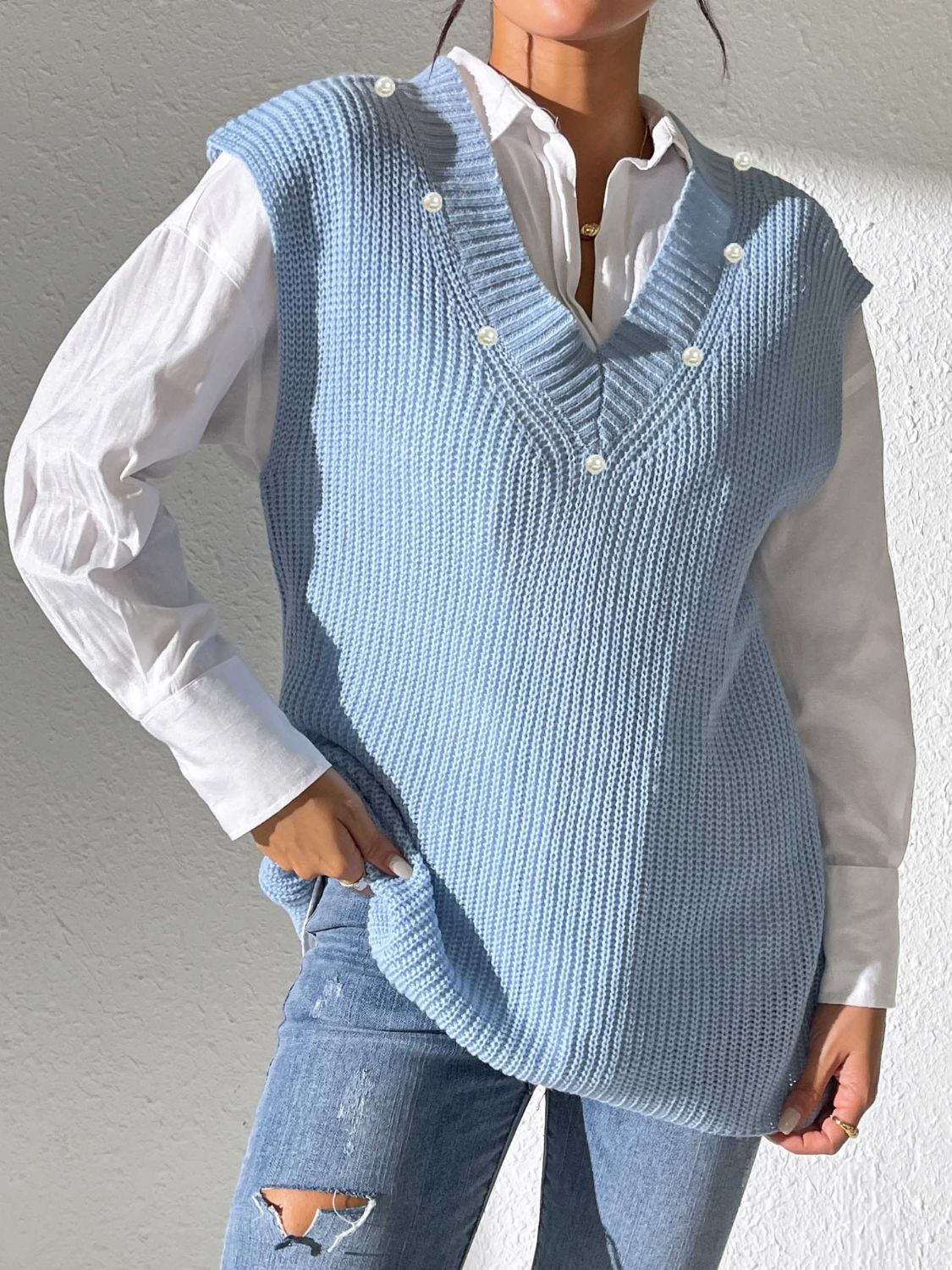 Light blue ribbed knit sleeveless vest with pearl buttons and V-neck.