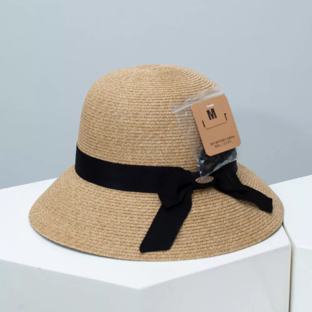 Straw bucket hat in Dust Storm with black ribbon detail and downturned brim.
