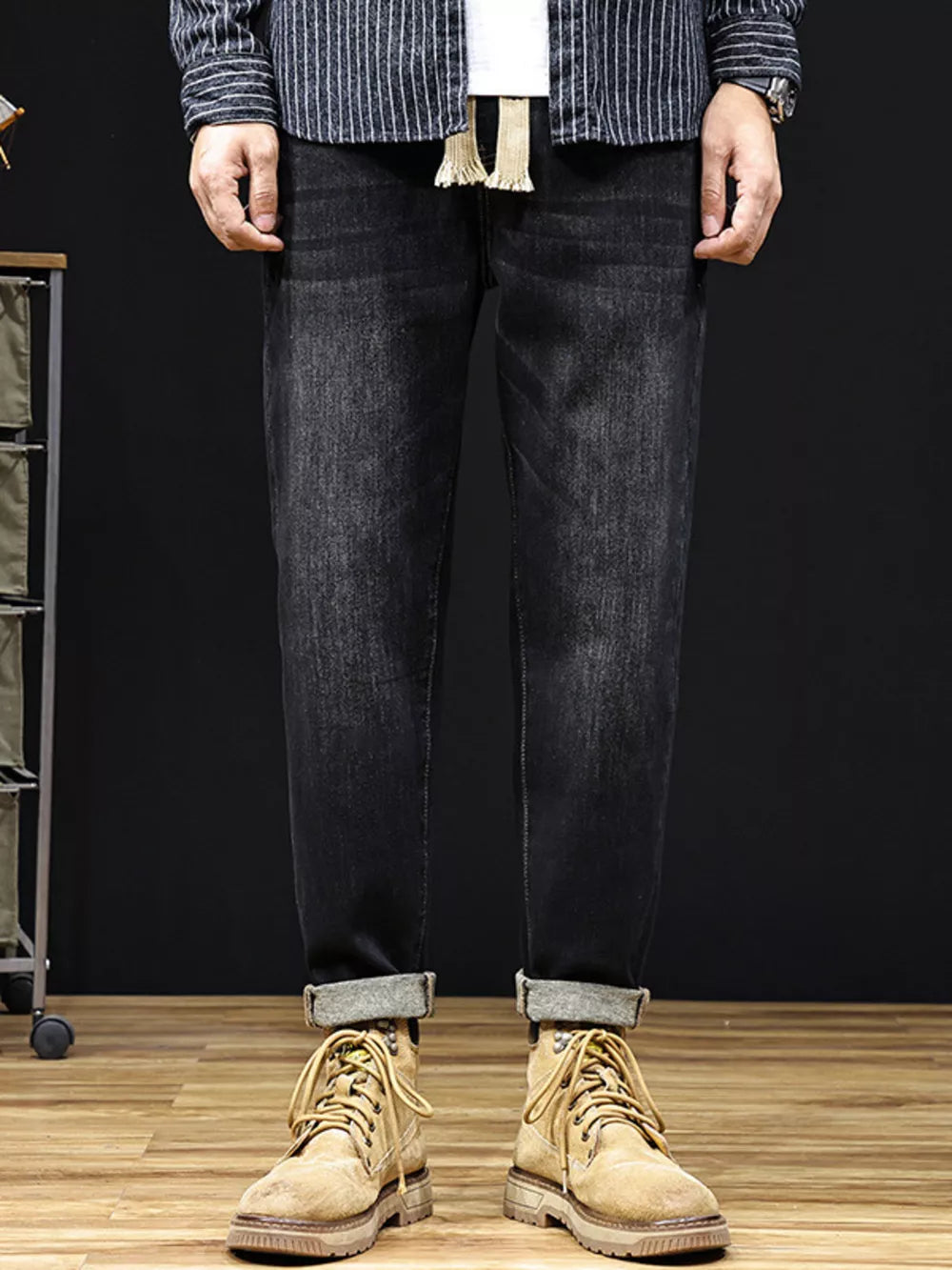 Men's black relaxed fit cotton jeans with drawstring detail and cuffed hems.