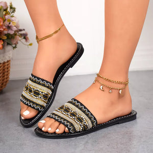Black embroidered artisan open-toe slide sandals with gold and white beadwork.
